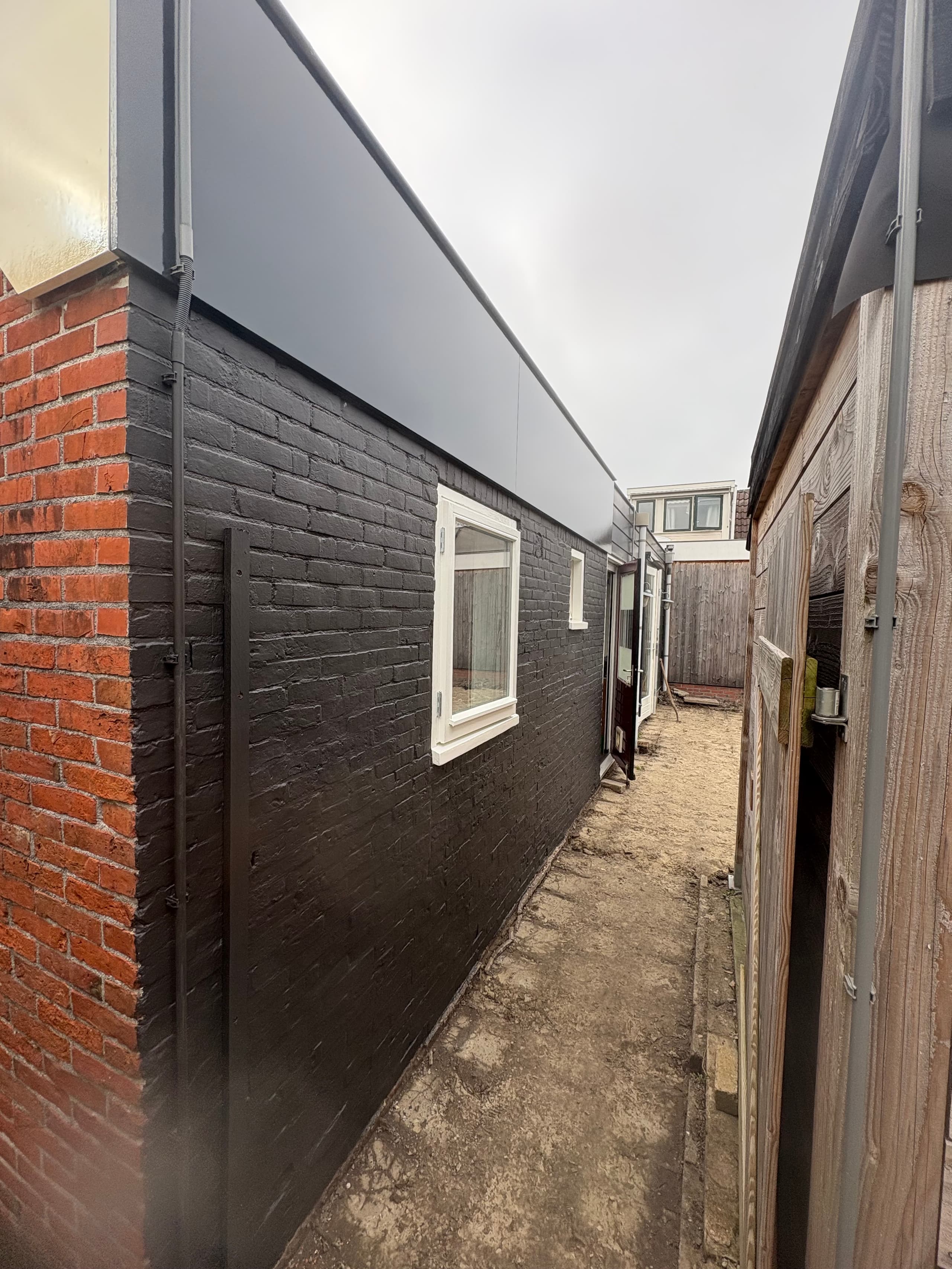 Antraciet metselwerk met witte kozijnen aan de achterzijde van een woning in Grypskerk