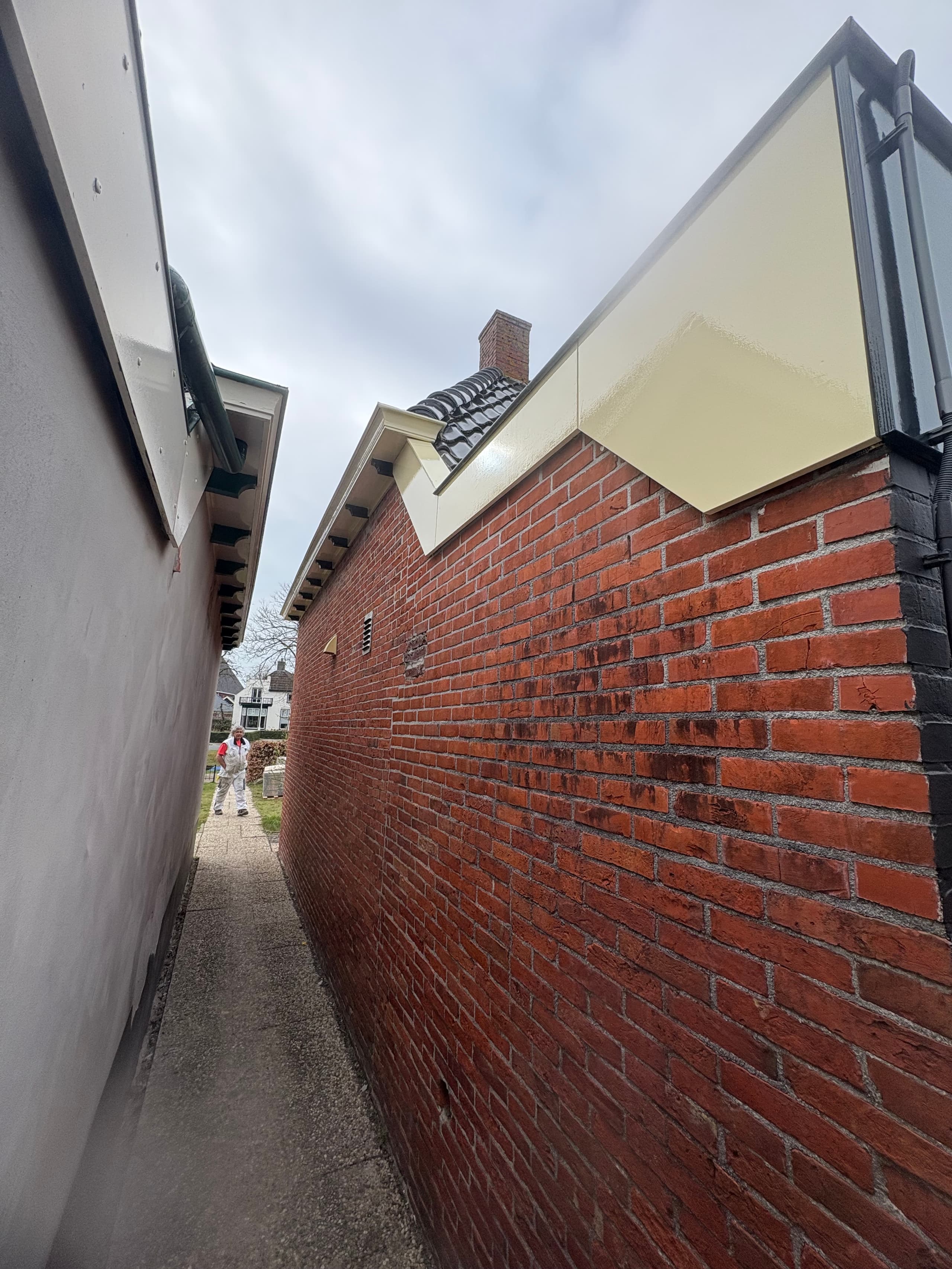 Crèmekleurig geschilderde houten boeidelen en lijstwerk langs de dakrand in Grypskerk