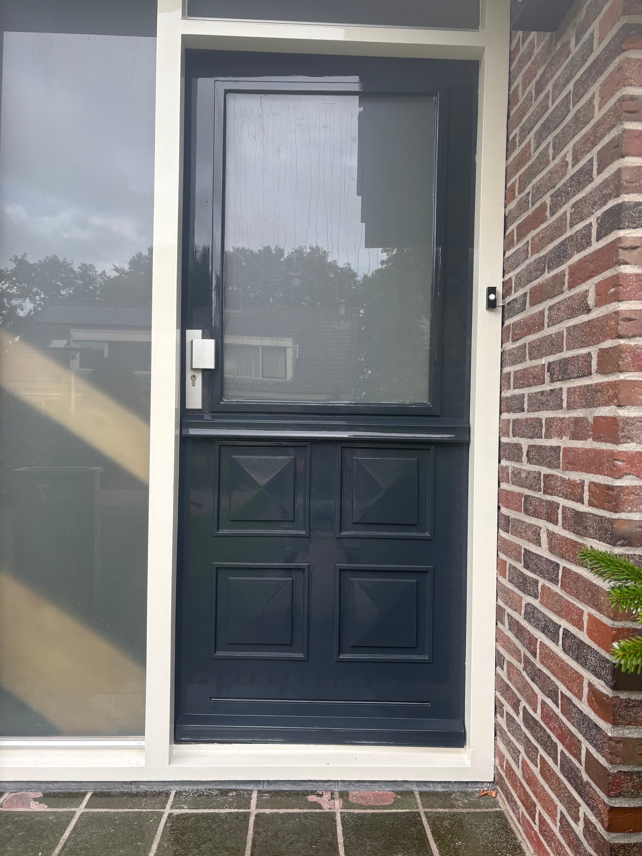 Diepzwarte hoogglans voordeur met zijlicht en strak lakwerk in Kollum