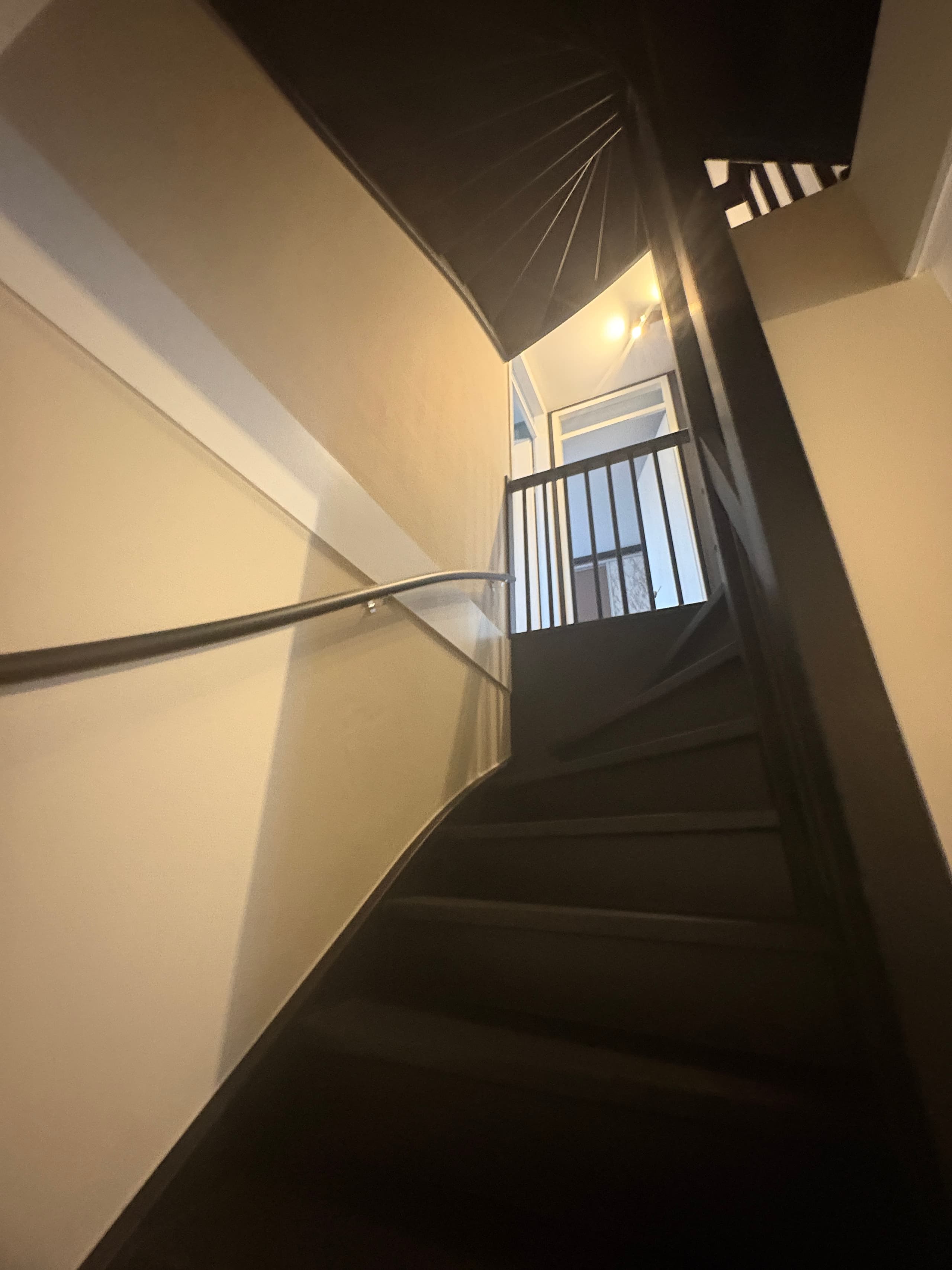 Donker geschilderde trap met spijlen en een lichte wand in een woning in Lemmer
