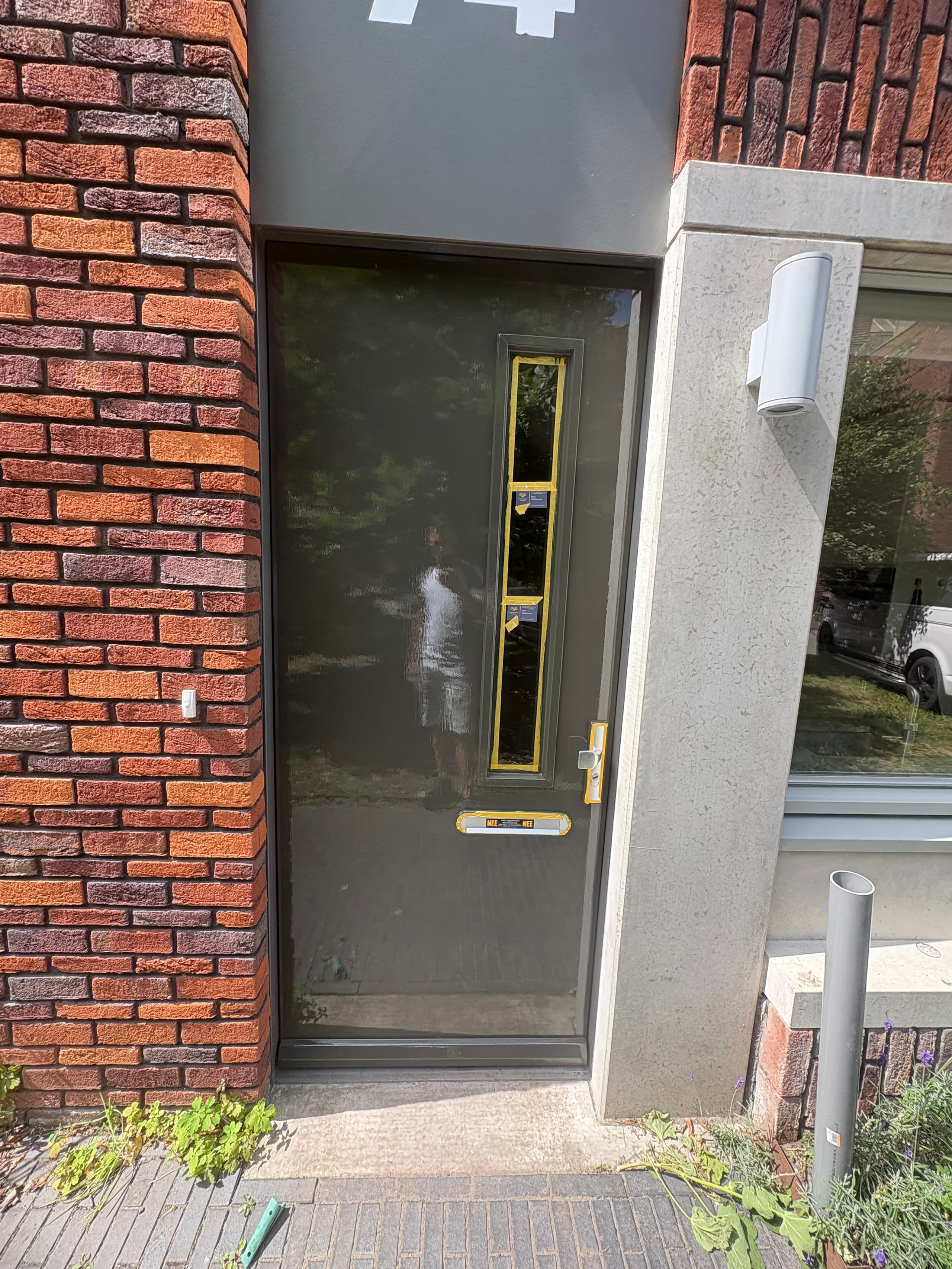 Grijze voordeur met gladde hoogglans afwerking als voorbeeld van schilderwerk