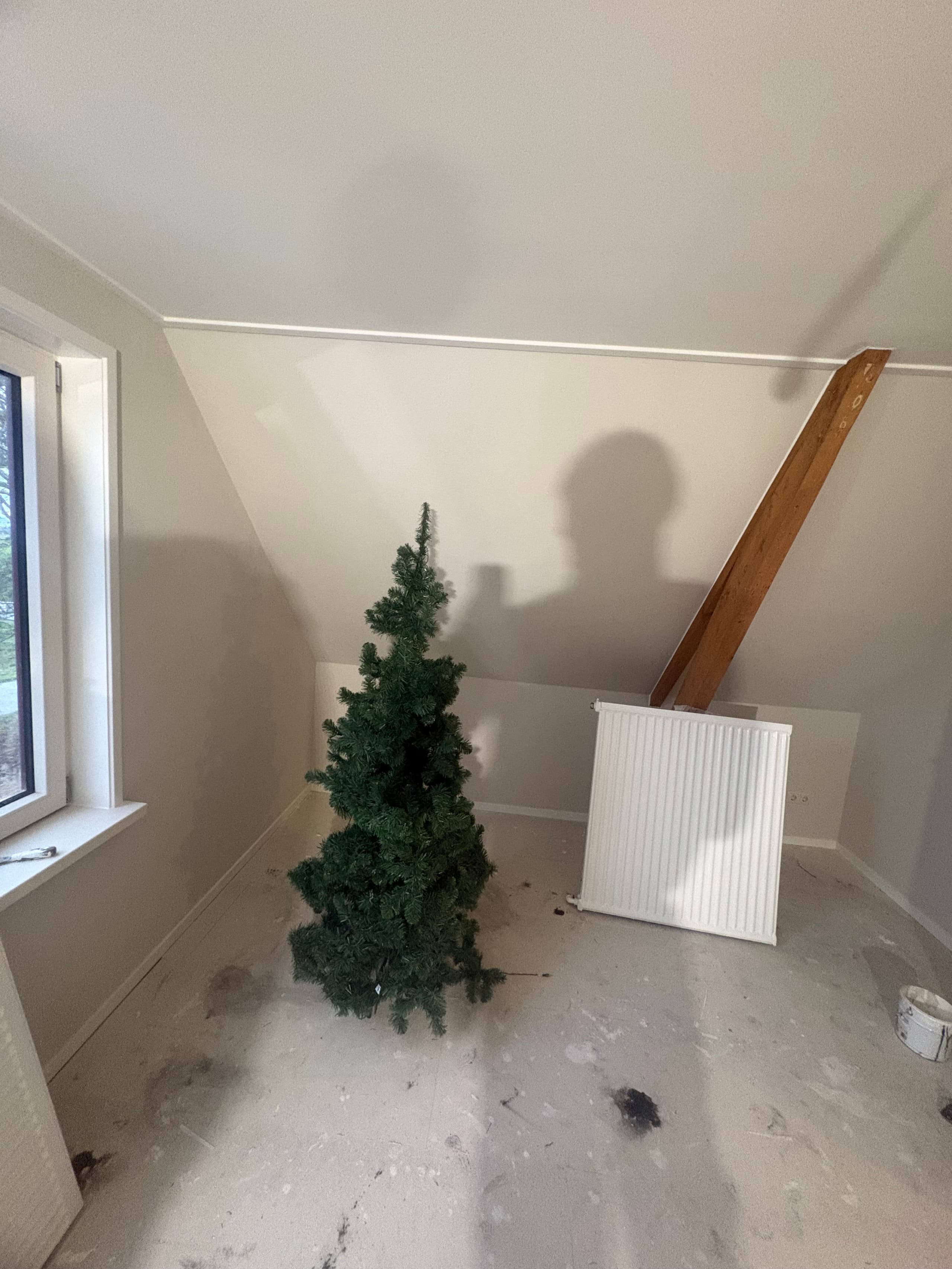 Lichte zolderkamer in Wanswert met witte wanden, schuin plafond en een houten balk